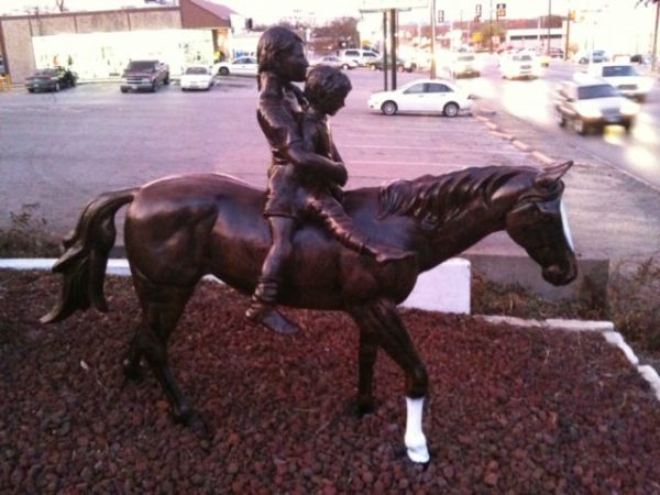 two children on horse aluminum statue side view in front yard